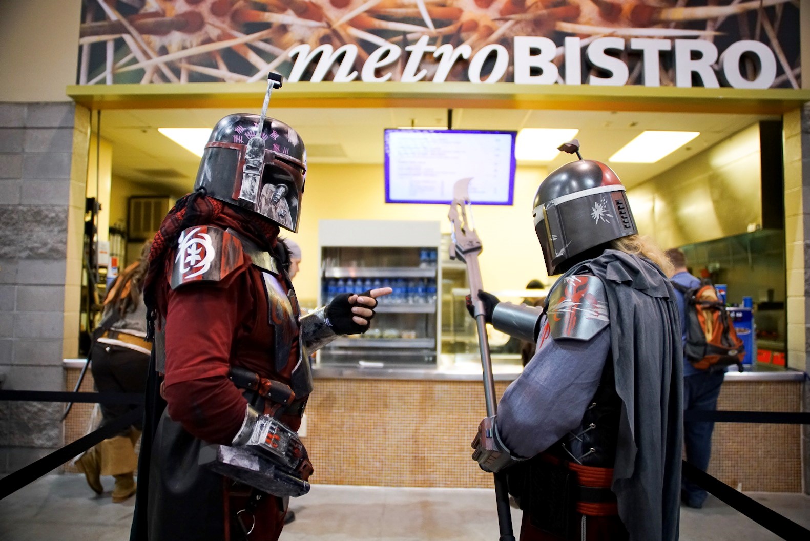 Two male characters inspecting a prop weapon